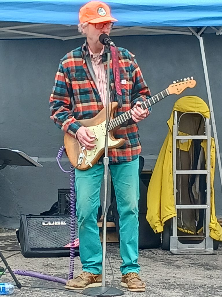 JOE PETE is 3'N1 playing solo guitar and singing outdoors on a cold day in May at Watertown Porch Fest.